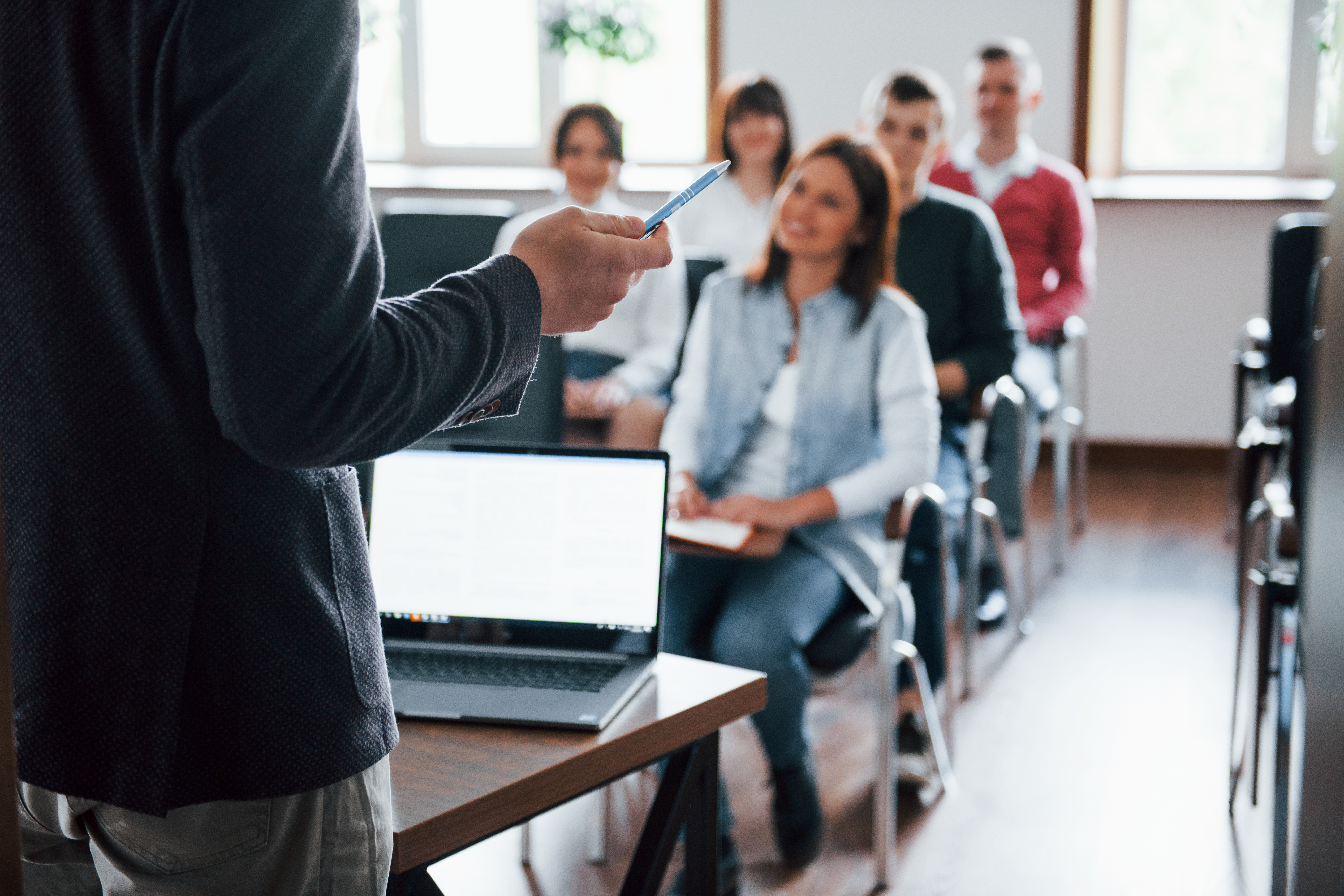 Todos sonríen y escuchan. Grupo de personas en una conferencia de negocios en un aula moderna durante el día.