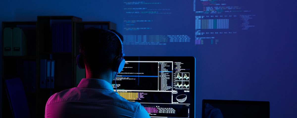 Developer working on code late at night, view from the back